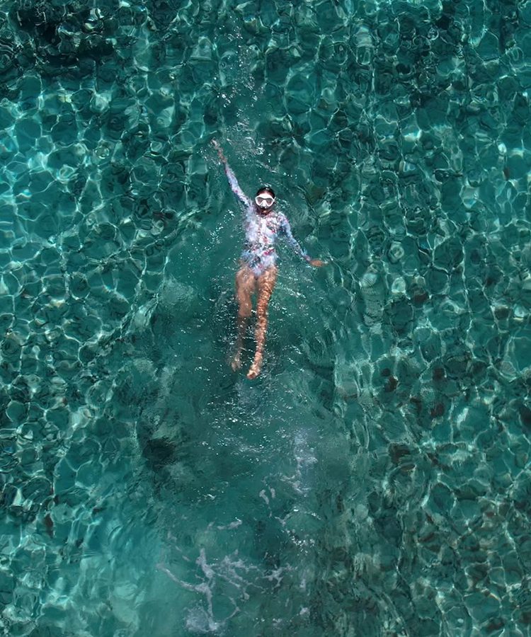 A person swimming in the water with their arms up.