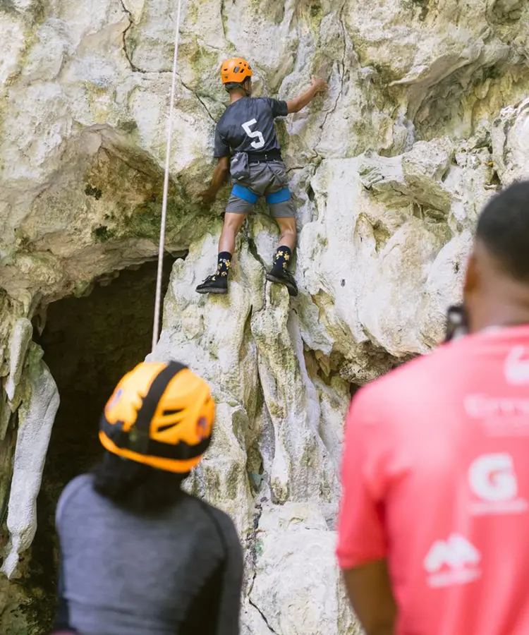 A man is climbing up the side of a rock wall.