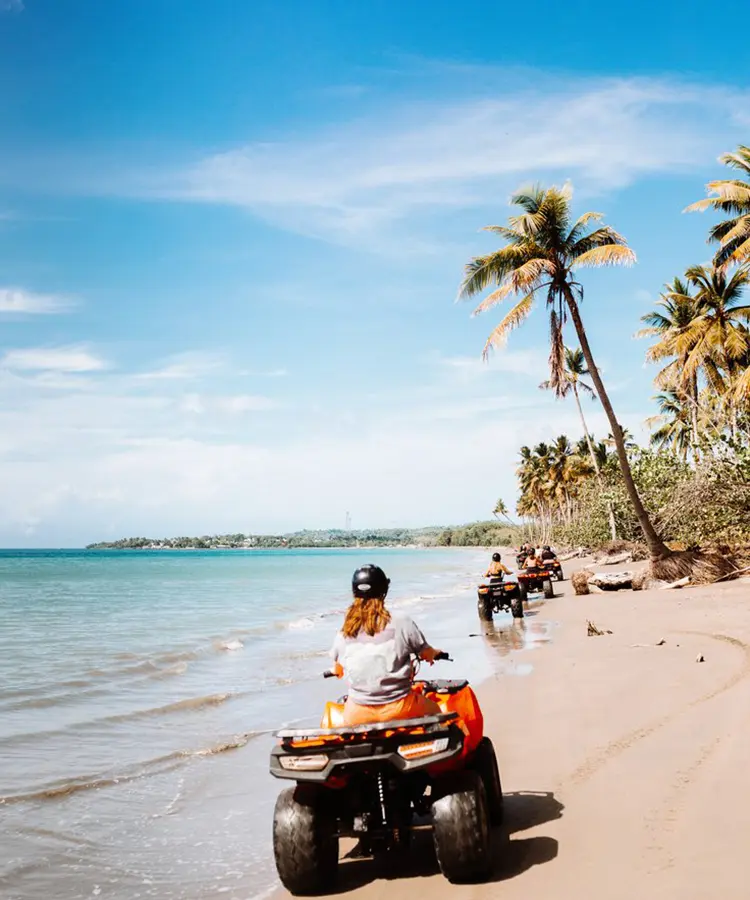 A group of people riding atvs on the beach.