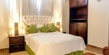 A bed with green pillows and white sheets.