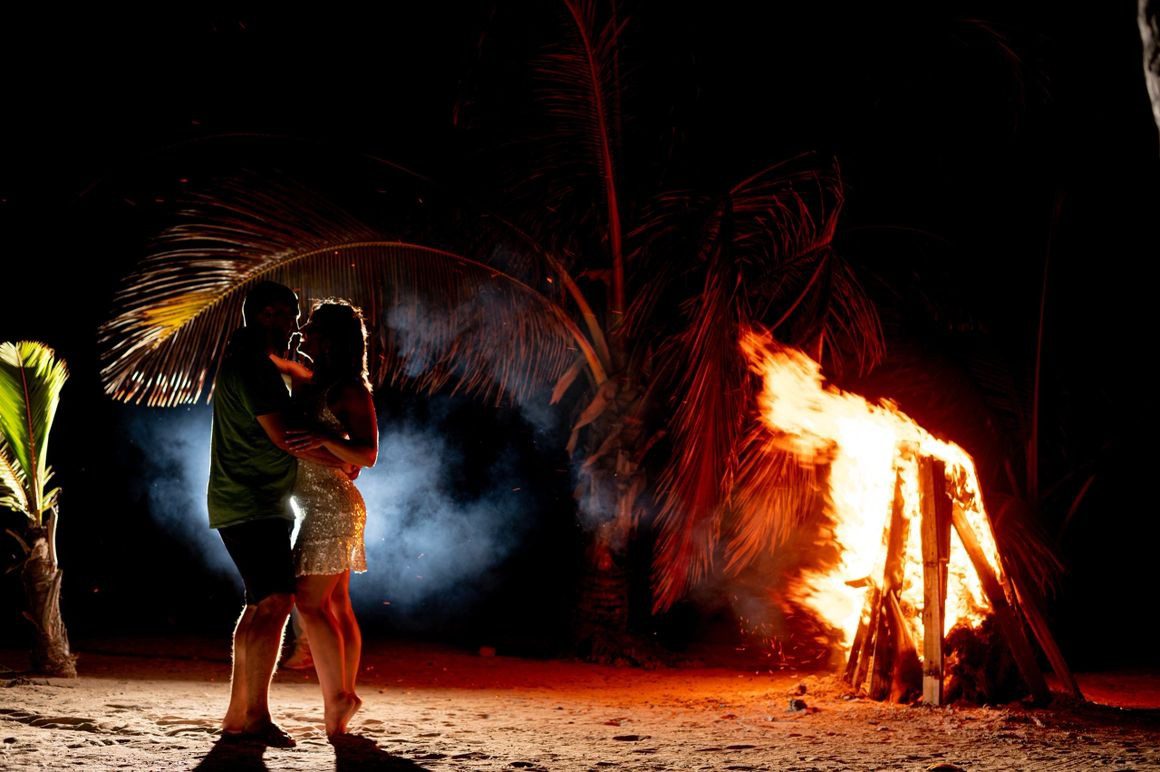 A couple is hugging in front of a fire.