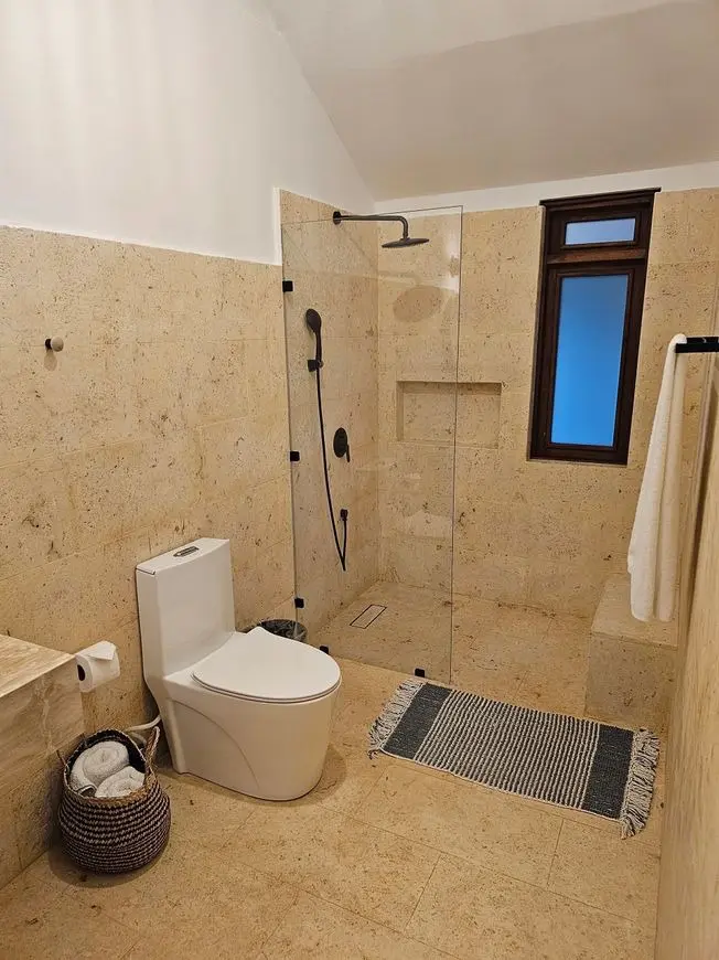 A bathroom with beige tile and white walls.