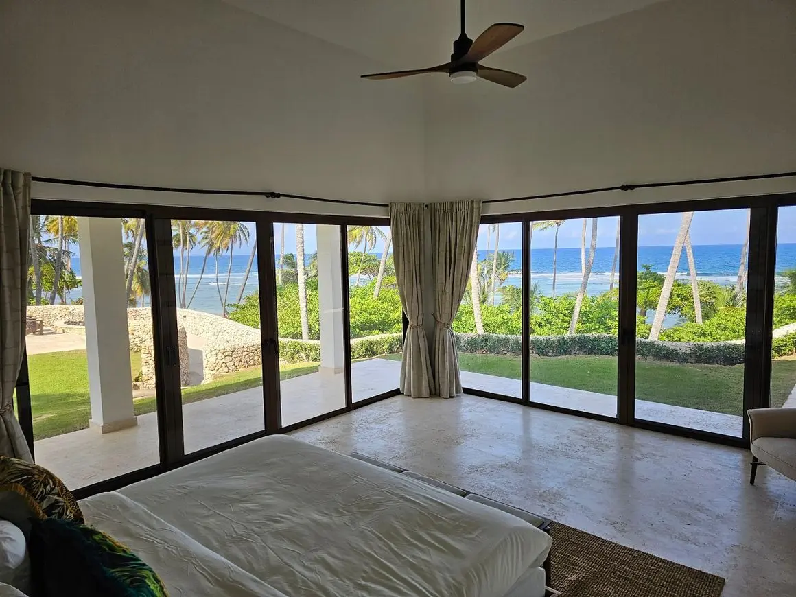 A bedroom with large windows and a view of the ocean.