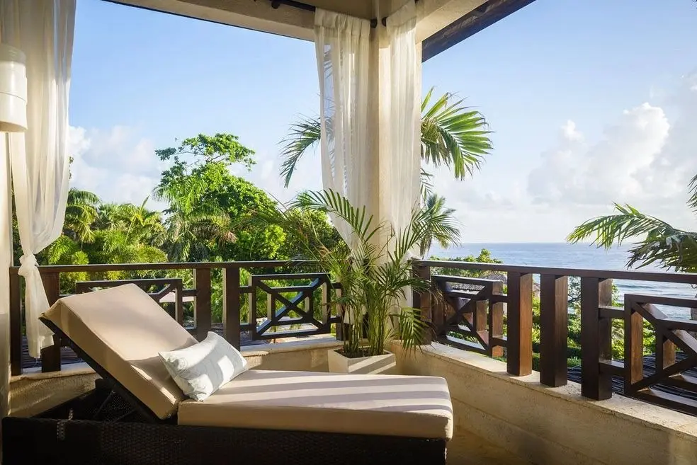 A balcony with a view of the ocean and palm trees.