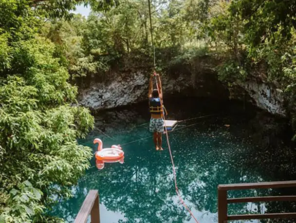 A person is hanging from a rope over the water.